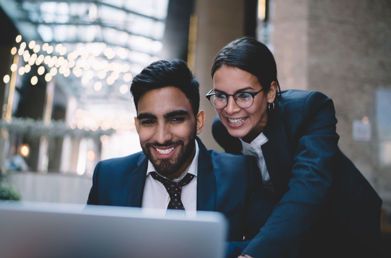 Dos personas sonrientes mirando un computador Dos personas sonrientes mirando un computador